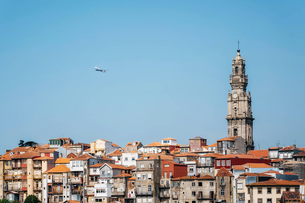 Porto Cityscape With Clerigos Tower and Airplane in Blue Sky, Portugal - Cheapest Time